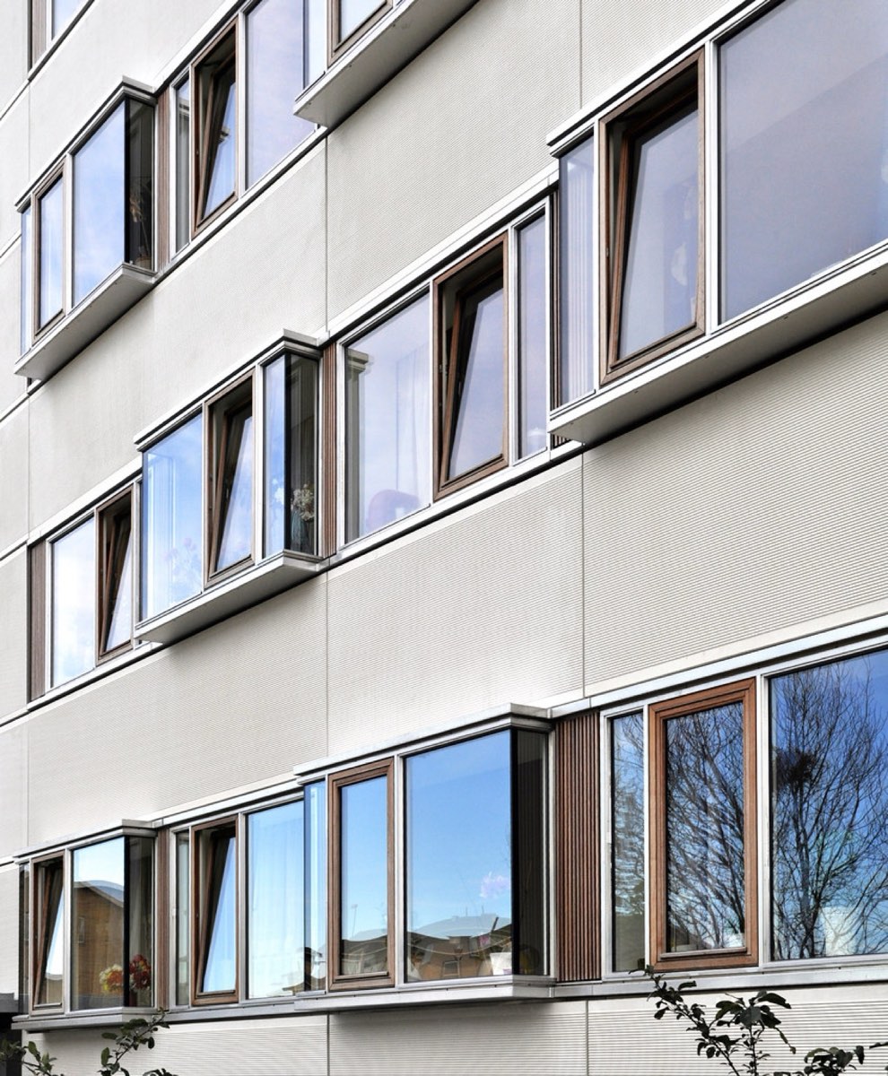 Sanierte Hausfassade mit neuen Holzfenstern in hellem Wärmedämmverbundsystem