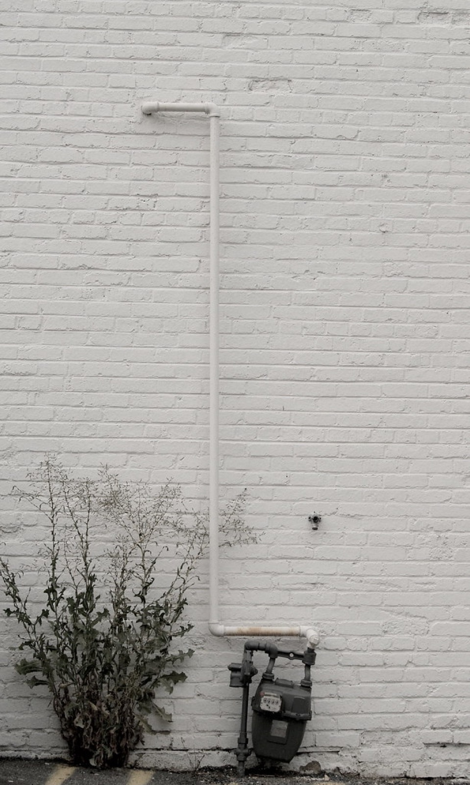 Gaszähler mit Leitung an einer weiß gestrichenen Ziegelwand